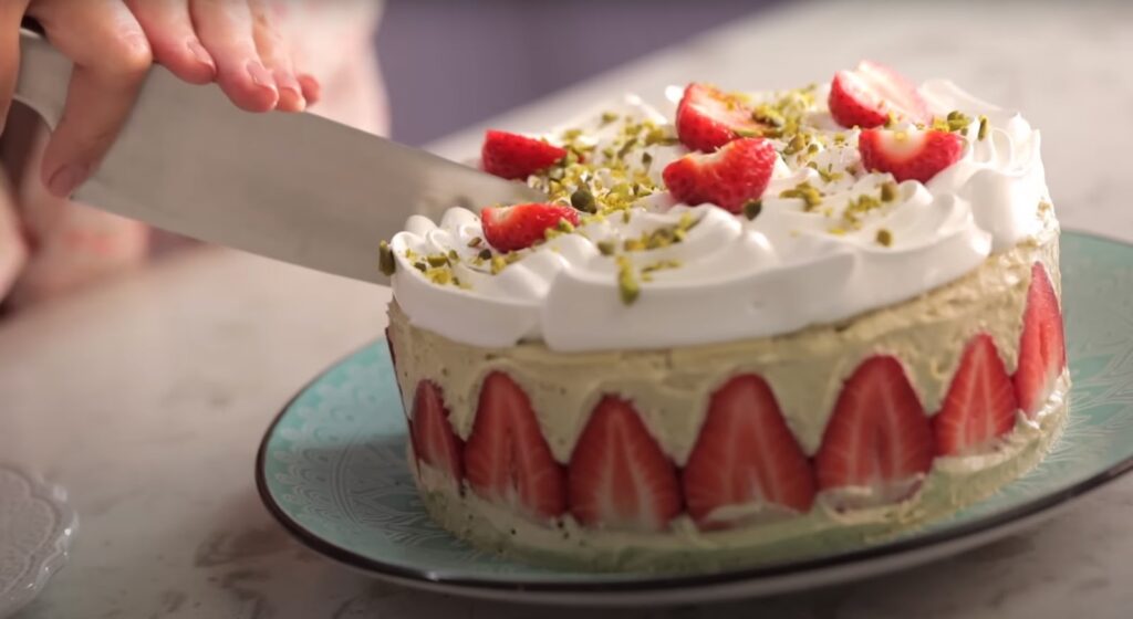 two hands cutting the Fraisier Cake with a knife