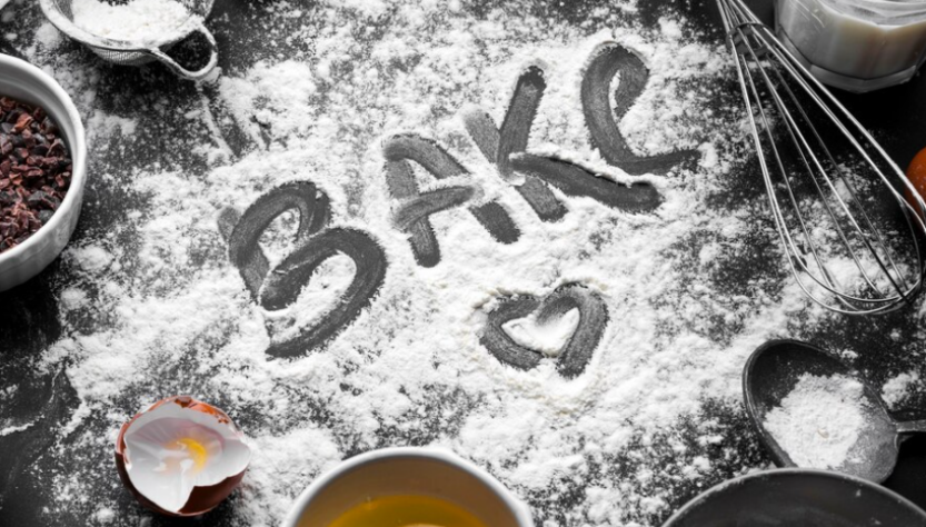 word bake written on a flour, dough whisk, and bowl with eggs