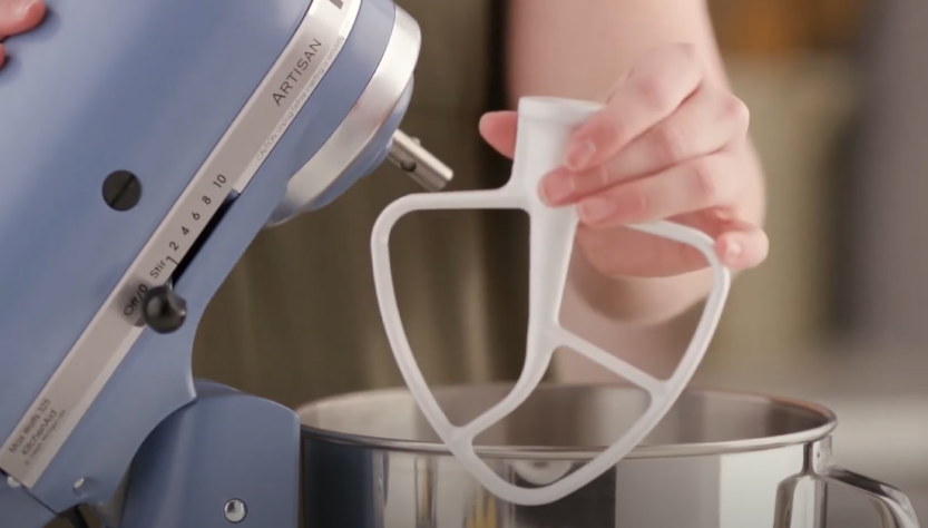 Close-up photo of KitchenAid Classic Flat Beater Attachment being detached by a woman's hand