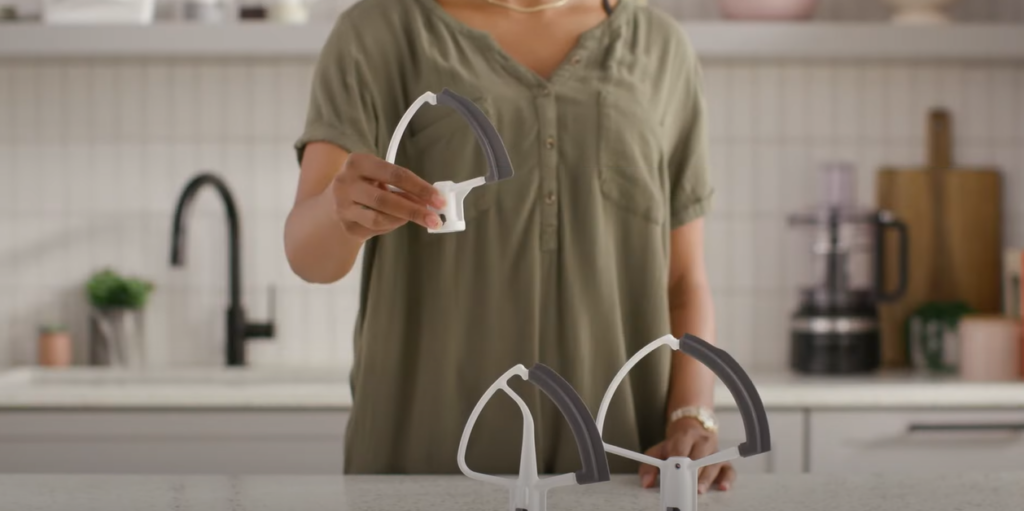  Two KitchenAid Flex Edge Beater Attachments on the table, one being held by a woman's hand