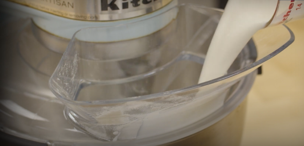 Close-up view of KitchenAid Pouring Shield with liquid being poured into it