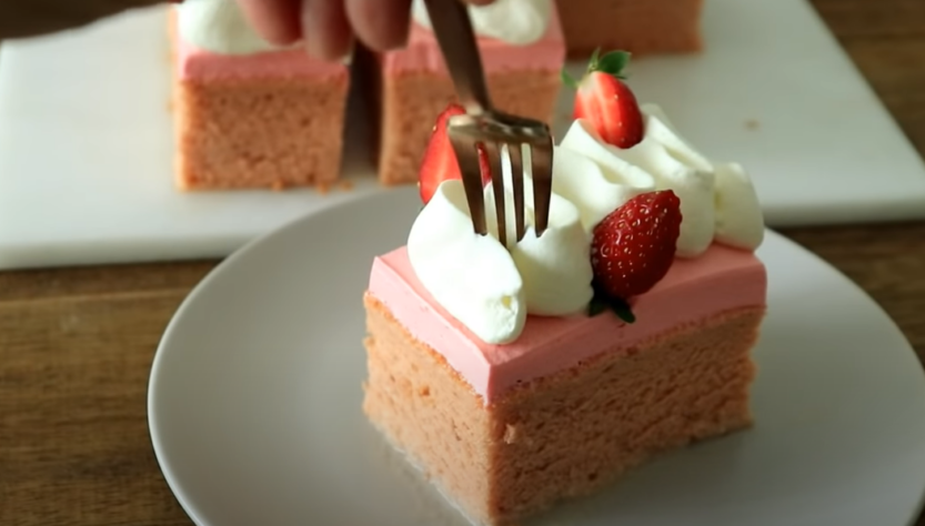 A piece of strawberry tres leches cake with a fork resting on top