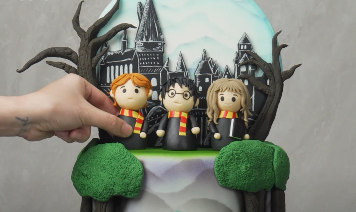Placing characters by hand on top of a cake