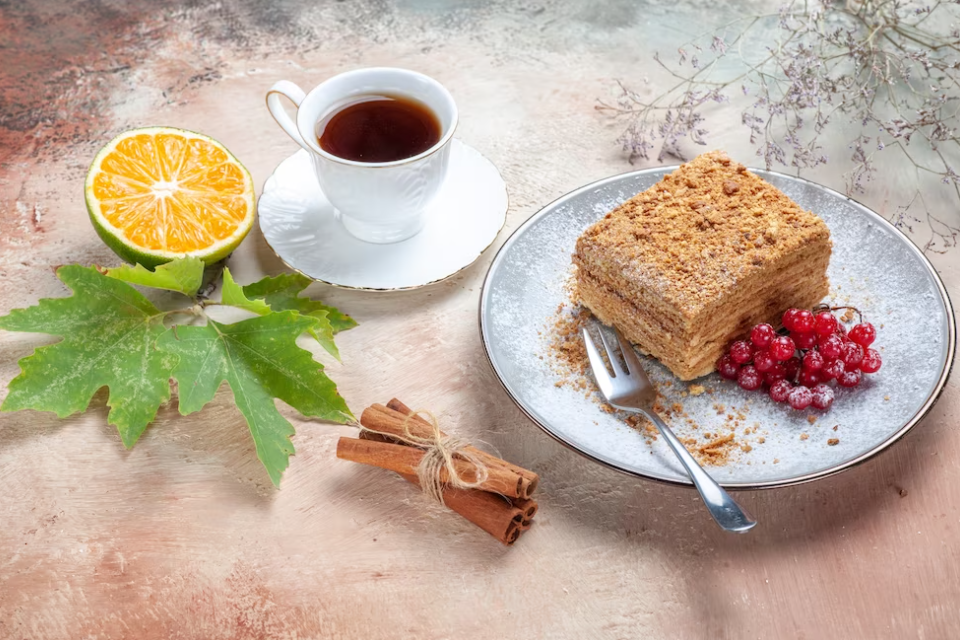 cup of tea, leaf, orange, vanilla, and cake with a fork on a plate