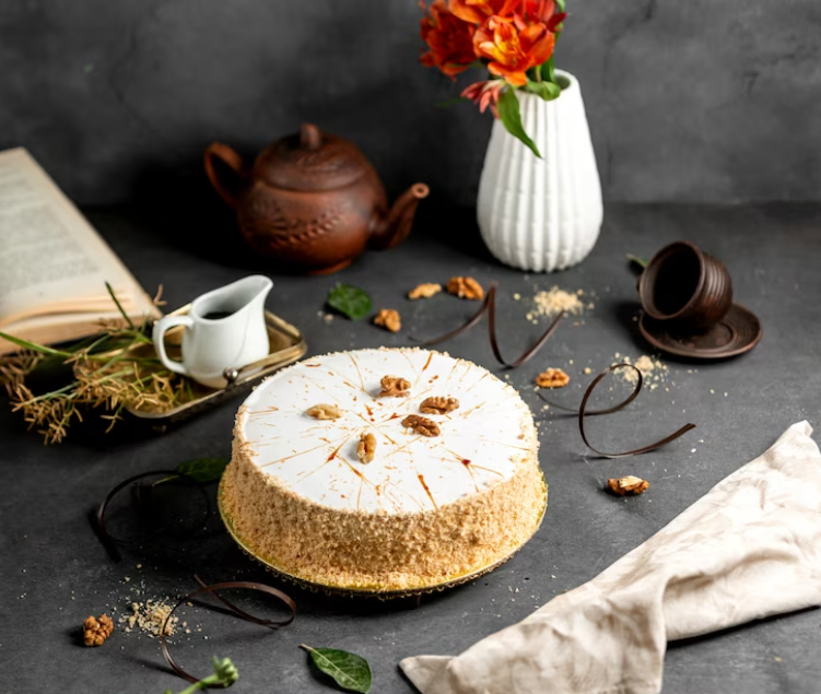 glazed cake decorated with cake crumbles and walnuts, towel, vase with a flower on the table